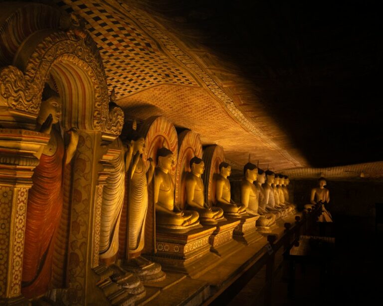 A row of golden Buddha statues inside a dim cave temple