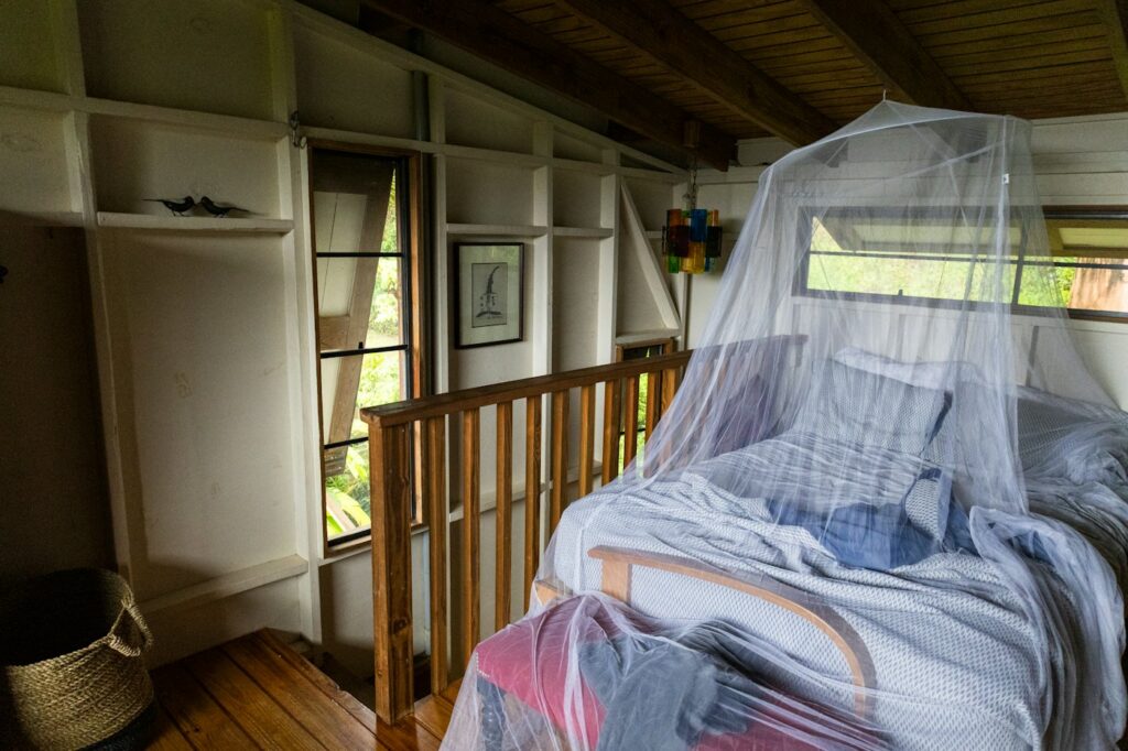 A simple bedroom with a mosquito net over the bed and wooden furniture