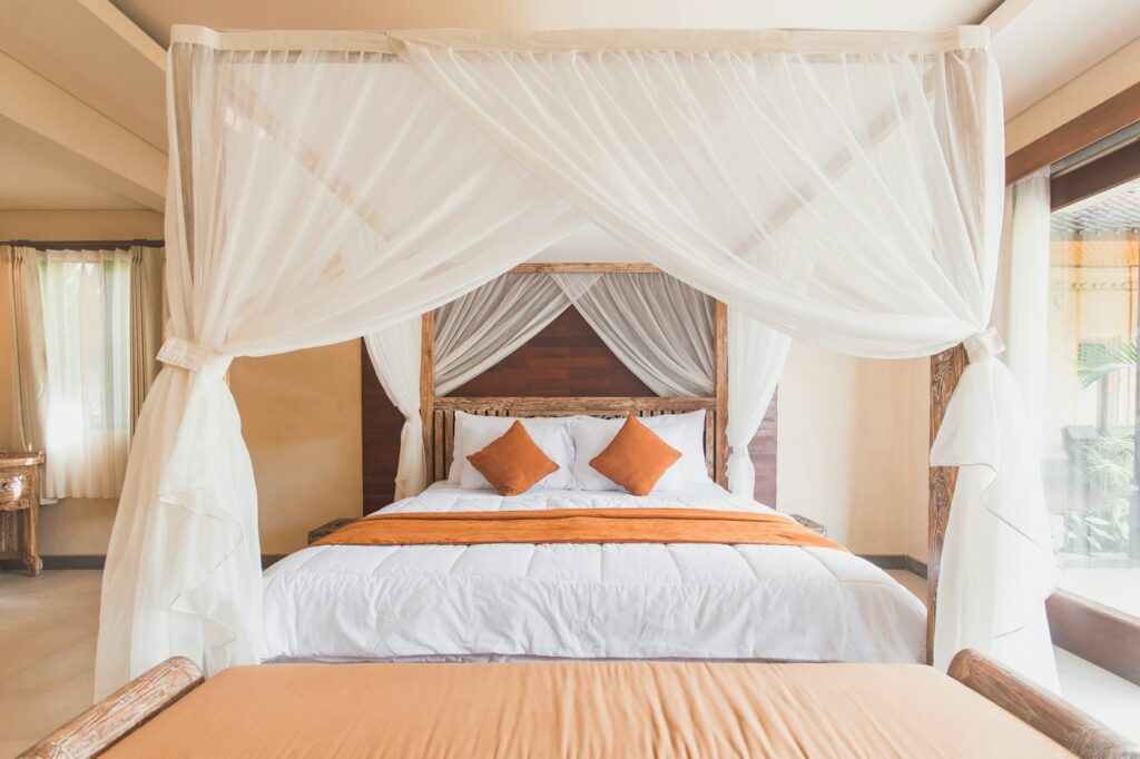 Deluxe Room with a canopy bed, mosquito net and orange cushions