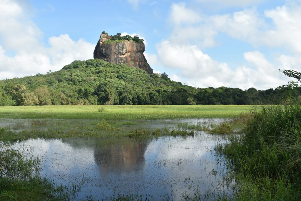 Sigiriya Rock seen across the calm water of a lake